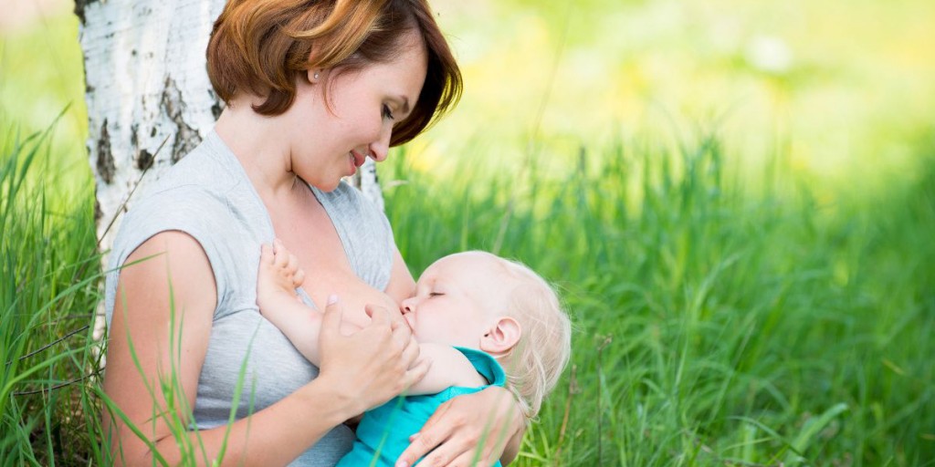 Young Mother Breastfeeding A Baby In Nature